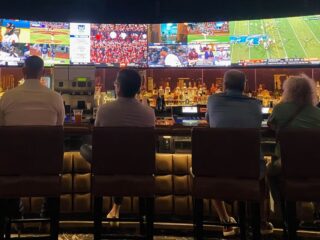 A group of people sitting at a bar watching TV