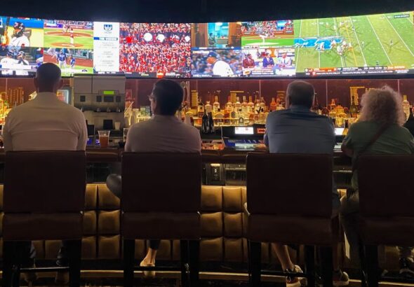 A group of people sitting at a bar watching TV